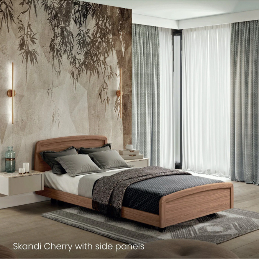 A modern bedroom featuring an Accora Contesa® FloorBed® Hi/Low Full Electric Bed in Skandi Cherry with side panels, grey and white bedding, floating nightstands, a nature mural, and large windows. A stylish fall-prevention solution.