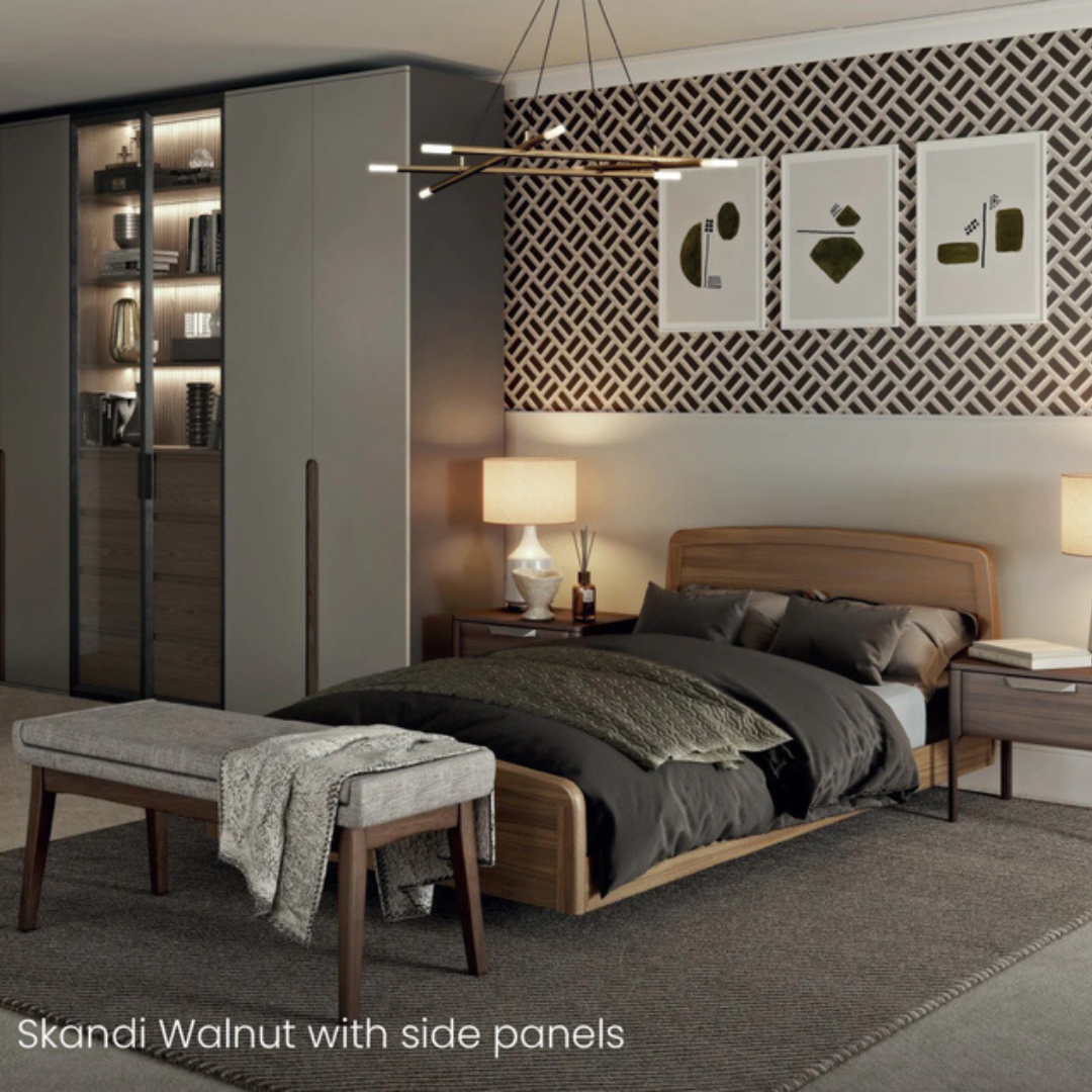 Modern bedroom with walnut bed frame, side tables, and bench. Featuring geometric wallpaper, glass-door wardrobe, abstract art, and warm lighting. The Accora Contesa® FloorBed® Hi/Low Full Electric Bed offers a stylish fall-prevention solution.