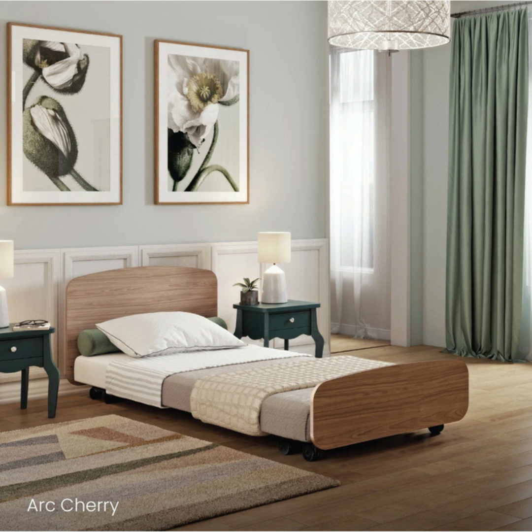 A modern bedroom with a single wooden Accora Contesa® FloorBed® Hi/Low Full Electric Bed, light bedding, two green nightstands with white lamps, floral wall art, tall window with green curtains, and a woven ceiling light. Text reads Arc Cherry.
