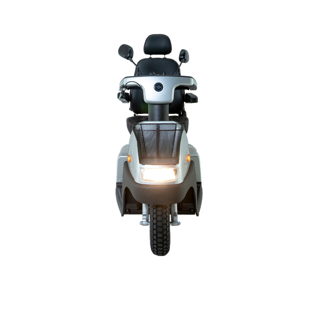 Front view of the Afikim Afiscooter C3 HD, a mid-size 3-wheel electric mobility scooter with a silver body, headlight on, black seat with armrests, rearview mirrors, and a front wire basket.