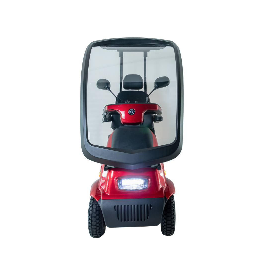 The Afikim Afiscooter C4 HD 4-Wheel Mobility Scooter is a modern red electric scooter with a sleek design, featuring large wheels, headlights, and a transparent enclosed canopy for a sheltered ride. Its orthopedic seat ensures comfort, making it ideal for mobility enthusiasts.