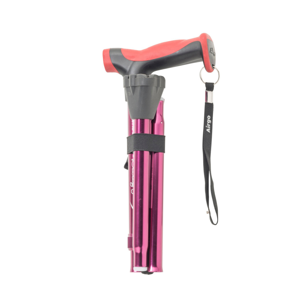 The Drive Airgo Comfort-Plus Folding Cane features an ergonomic red and black handle, metallic pink shaft, and black wrist strap—secured with a Velcro strap—designed to be arthritis-friendly for enhanced comfort.