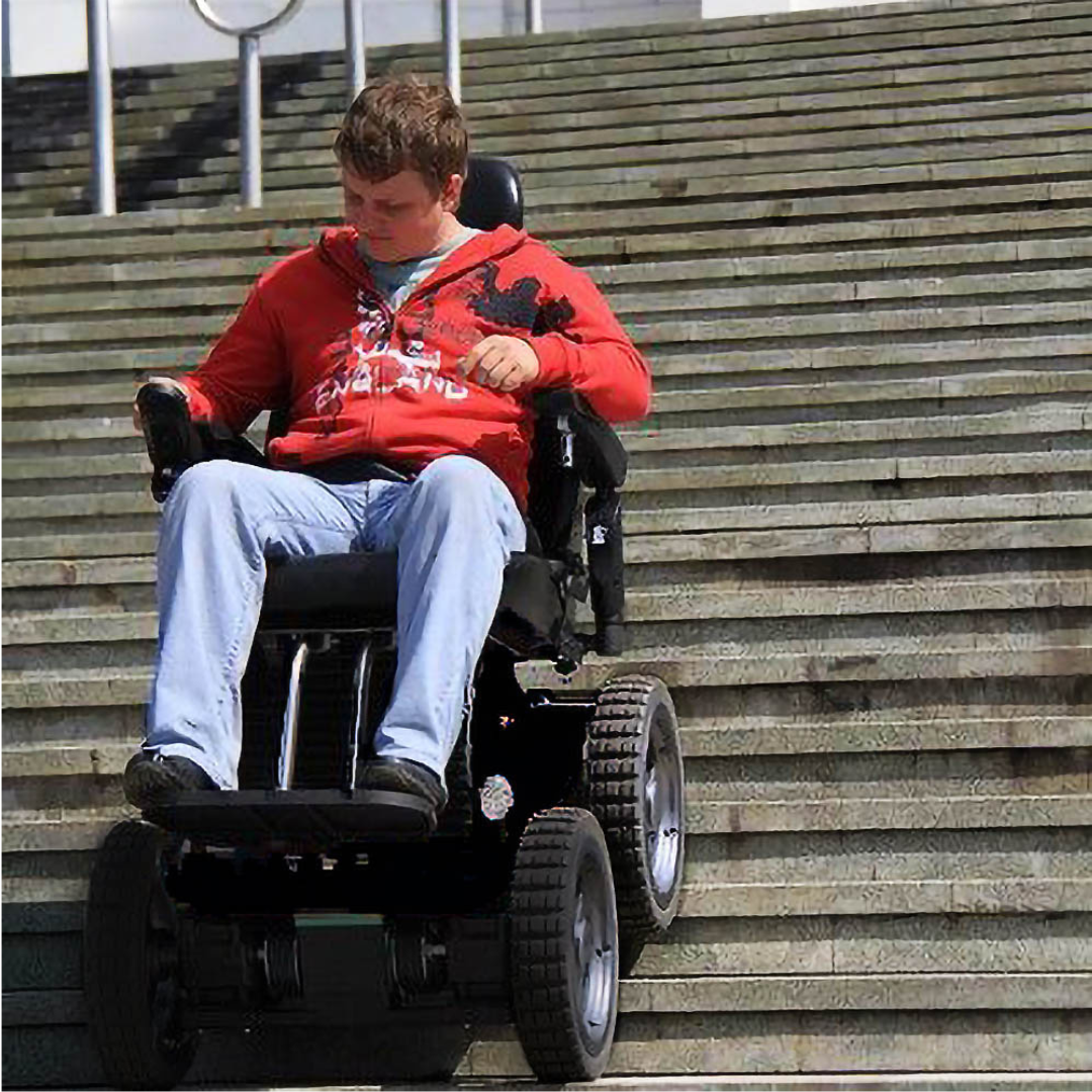A man in a red jacket and blue jeans skillfully descends a wide outdoor staircase using the Wheelchair88 All-Terrain Stair Climbing 4x4 Recreational Electric Vehicle, which features large rugged wheels for enhanced mobility.