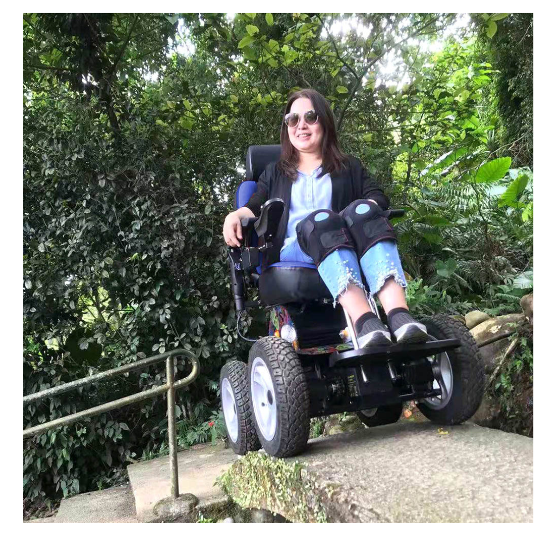 A smiling woman with leg braces enjoys the outdoors, sitting in a Wheelchair88 All-Terrain Stair Climbing 4x4 Recreational Electric Vehicle on a stone path surrounded by lush greenery and trees.