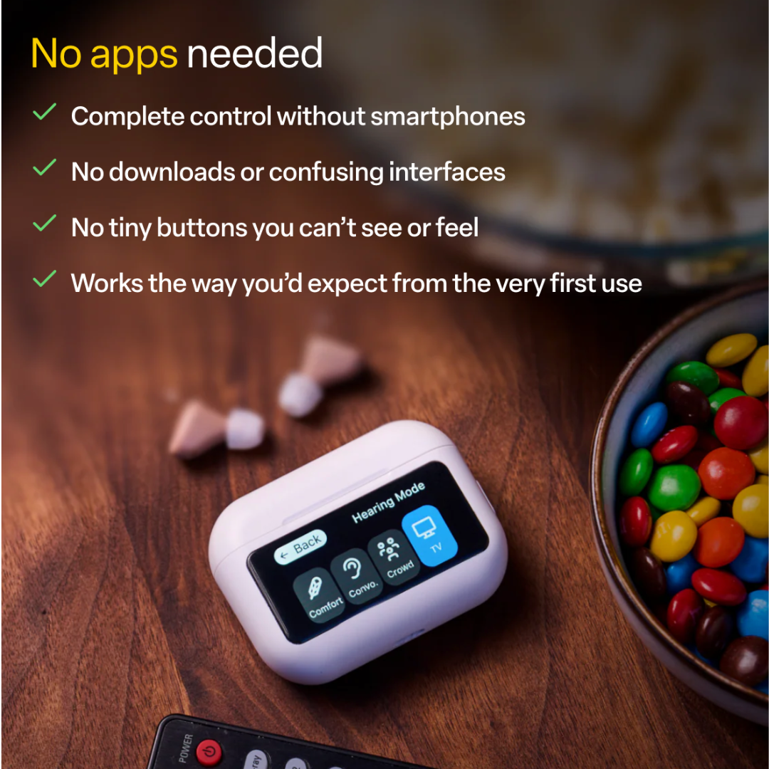 The Audien Hearing Atom X Hearing Aids with Digital Case Control, featuring easy button controls and no apps required, sits on a table beside TV remotes, earplugs, and a bowl of colorful candies.