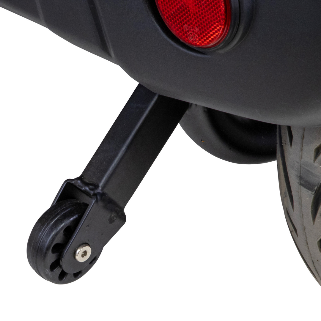 A close-up of a small black training wheel attached to the rear of a Bespoke Legacy Recreational 3-Wheel Scooter, with part of a tire and a red reflector also in view.