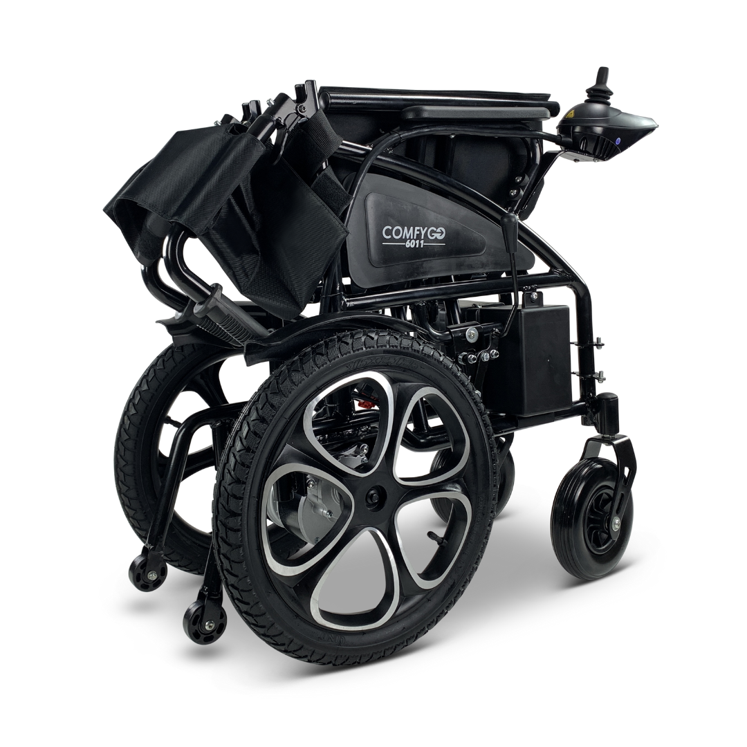 The ComfyGO 6011 is a lightweight, foldable black electric wheelchair with large rear wheels and small front castors. It has a joystick control on the armrest, a folded footrest, and displays the label COMFYGO along with model number 601.