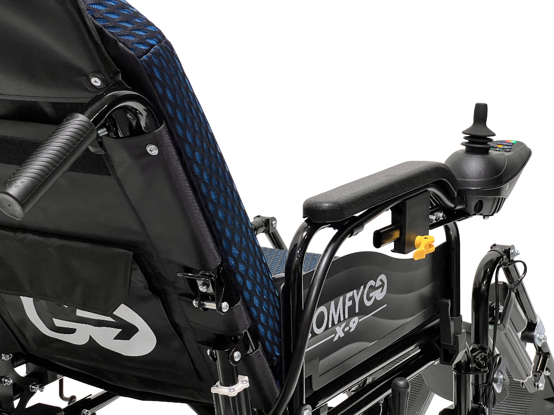 Close-up of the ComfyGo X-9 electric wheelchair featuring a blue mesh seat and joystick control on the armrest. This advanced mobility solution includes a storage pouch with logo and model name OMFYGO X-9 on the side.