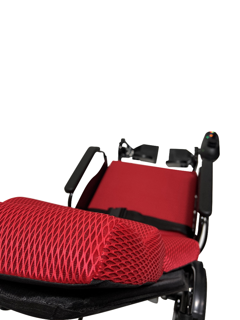 The ComfyGo X-9 Remote Controlled Powerchair, featuring an automatic reclining seat in red and black with breathable mesh fabric, is shown up close against a black background. The innovative mobility solution includes a visible control joystick on the armrest.