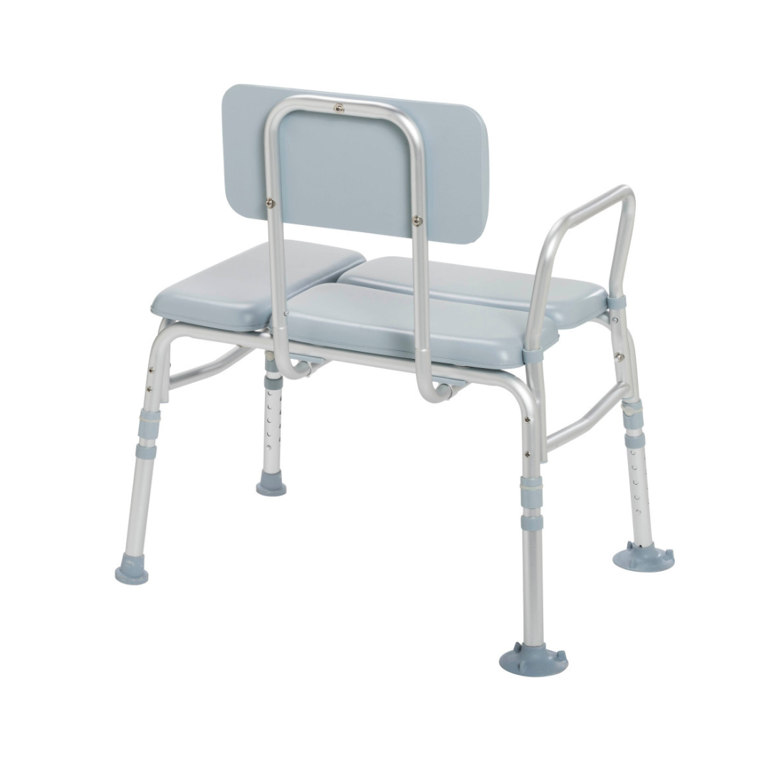 The Drive Medical Bariatric Padded Transfer Bench features a light blue and silver design with padded seat, backrest, and armrest, offering a safe adjustable transfer solution for getting in and out of the bathtub or shower.