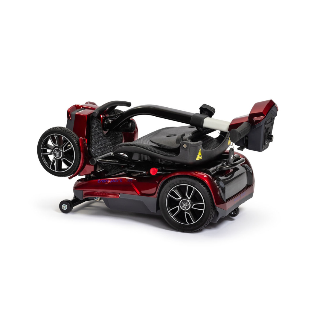 The EV Rider Transport 4M Travel Scooter is a compact, shiny red lightweight scooter with black wheels, silver hubcaps, and a seat that folds neatly within the frame for easy storage or transport.