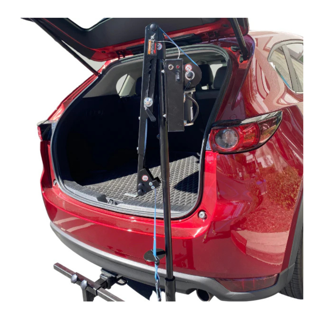 A red SUV with its rear hatch open features the FreeRider Scooter Lift For Vehicles, a black portable mobility lift mounted on the back, used for loading or unloading heavy items into the cargo area.