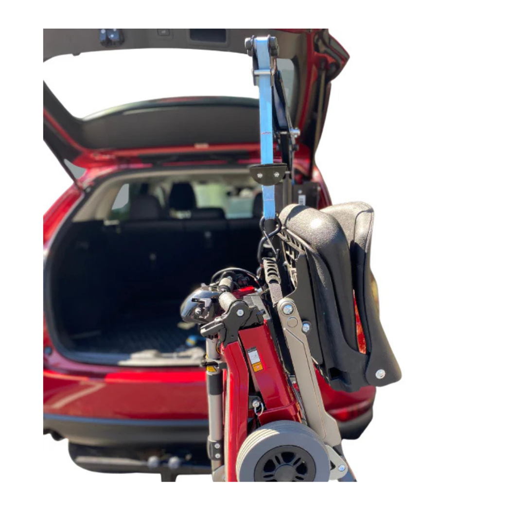 The FreeRider Scooter Lift For Vehicles is shown lifting a mobility scooter into the open trunk of a red SUV. The white background emphasizes the car and scooter, showcasing the convenience of the FreeRider lift in action.