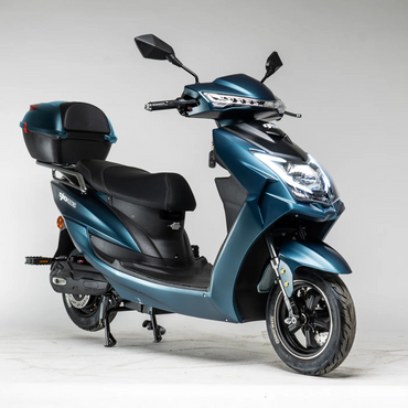 The GIO Phoenix Premium Electric Scooter in teal features a black seat and rear storage box, parked on its center stand in a bright studio with a plain light background—no license required.