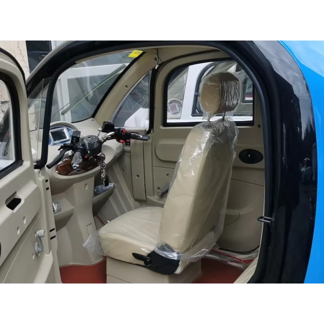 The image shows the interior of the GIO Golf Fully Enclosed Mobility Scooter with Heater and Cooling Fan, featuring beige seats in protective plastic and a visible drivers seat and dashboard through an open door.