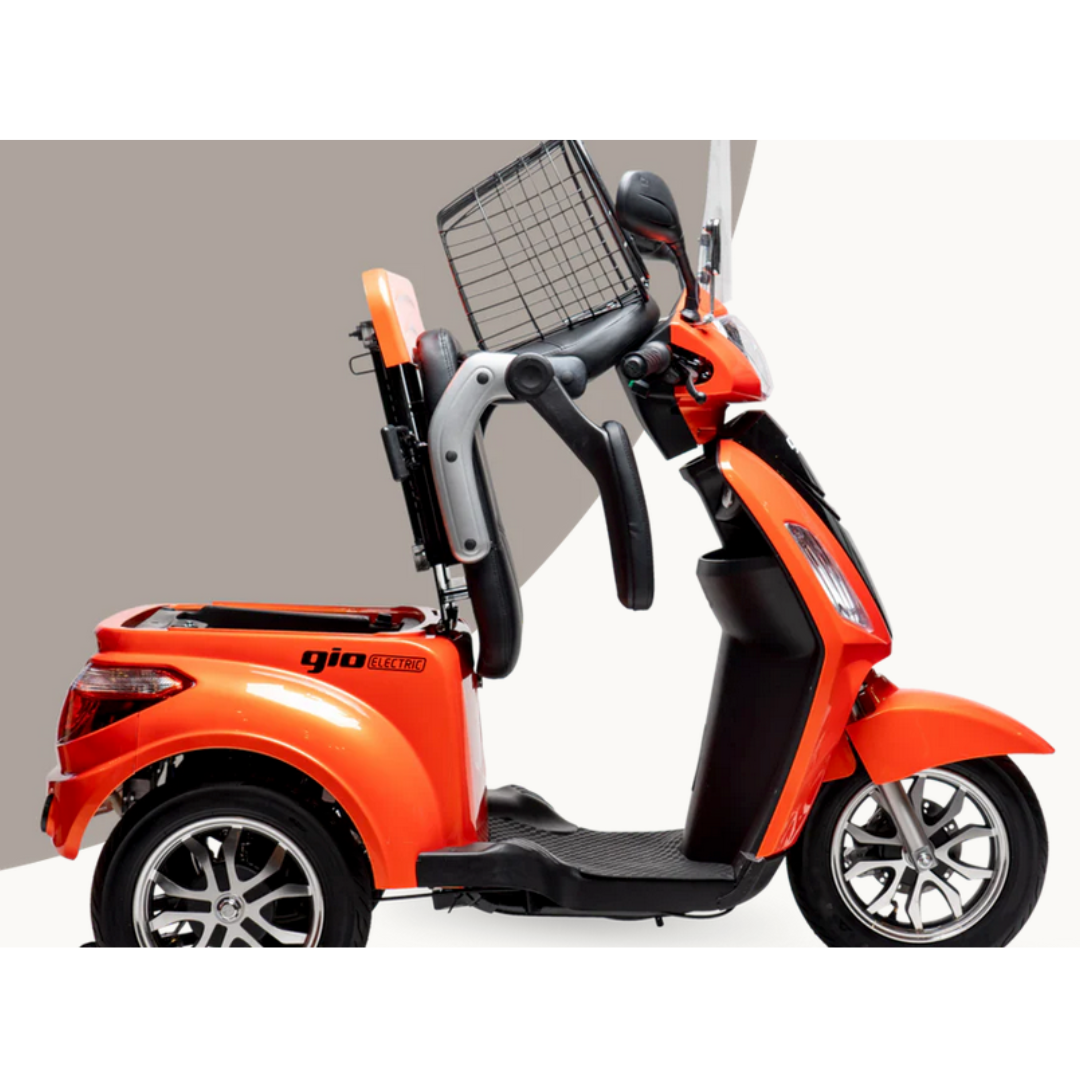 The GIO Regal HD Bariatric Mobility Scooter, shown in profile, features a bright orange color, three wheels, an elevated seat with backrest and armrests, and a rear metal basket. It’s powered by a 500W motor against a geometric beige-and-white background.