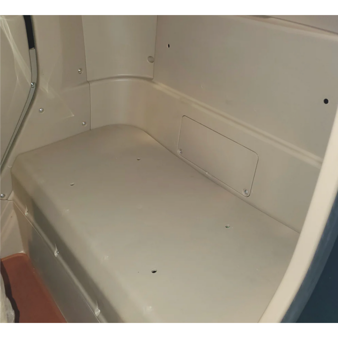 Inside the beige portable restroom, its bench-like seat and rectangular side panel echo the sleek minimalism of a GIO Golf Fully Enclosed Mobility Scooter. Neutral lighting accentuates its smooth surfaces and simple design.