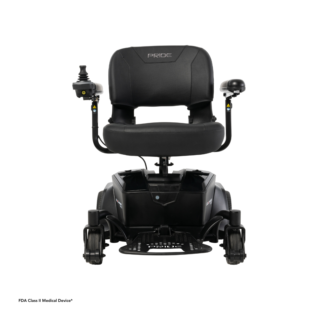 The Pride Mobility Go Chair® MED Portable Powerchair, shown from the front against a white background, is black with armrests, left-side joystick control, and four wheels. The Pride brand name appears on the seat back.
