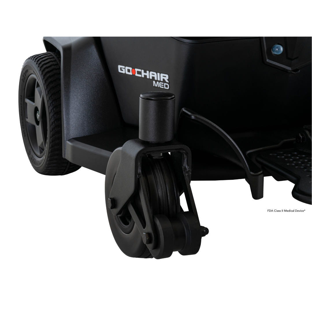 Close-up of the front wheel and frame of the Pride Mobility Go Chair® MED Portable Powerchair, highlighting its logo and durable caster wheel—perfect for those needing a lightweight, travel-friendly mobility solution.