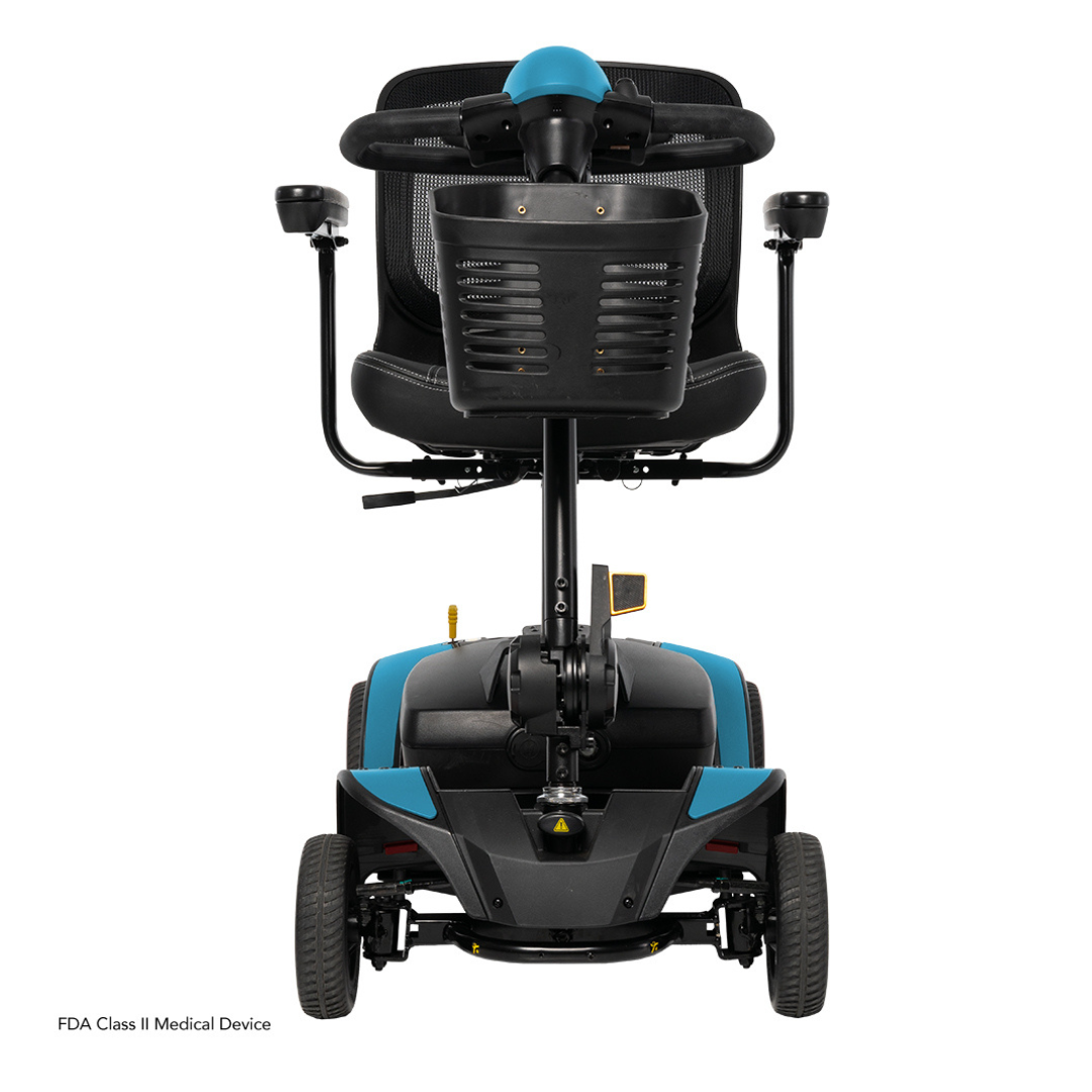 A rear view of the Pride Mobility Go Go Elite Traveller® 2 Platinum Scooter shows a black seat with armrests and backrest, a blue base, four wheels, and control handles. “FDA Class II Medical Device” appears in the lower left corner.