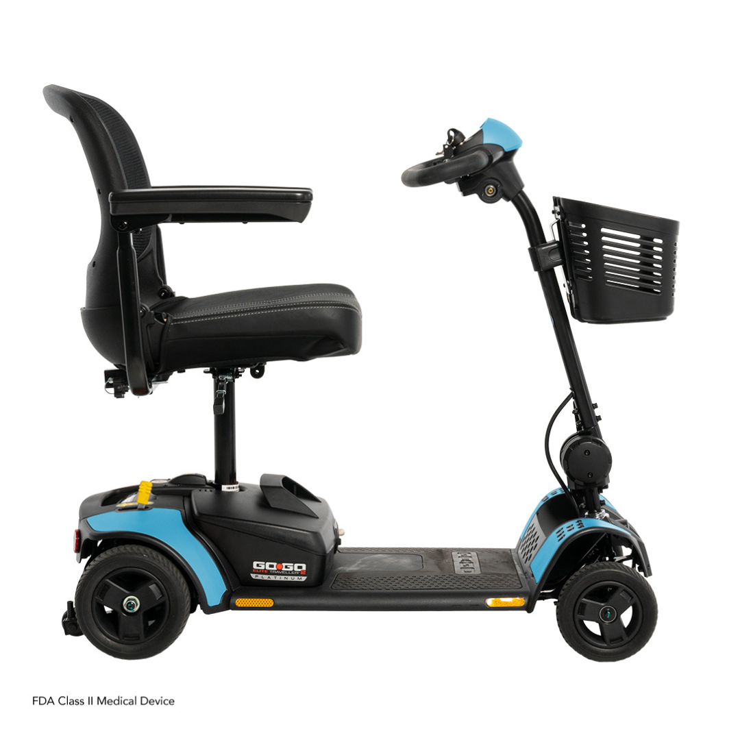 The Pride Mobility Go Go Elite Traveller® 2 Platinum Scooter, shown from the side on a white background, features blue and black colors, a padded seat with armrests, three wheels, and a front basket.