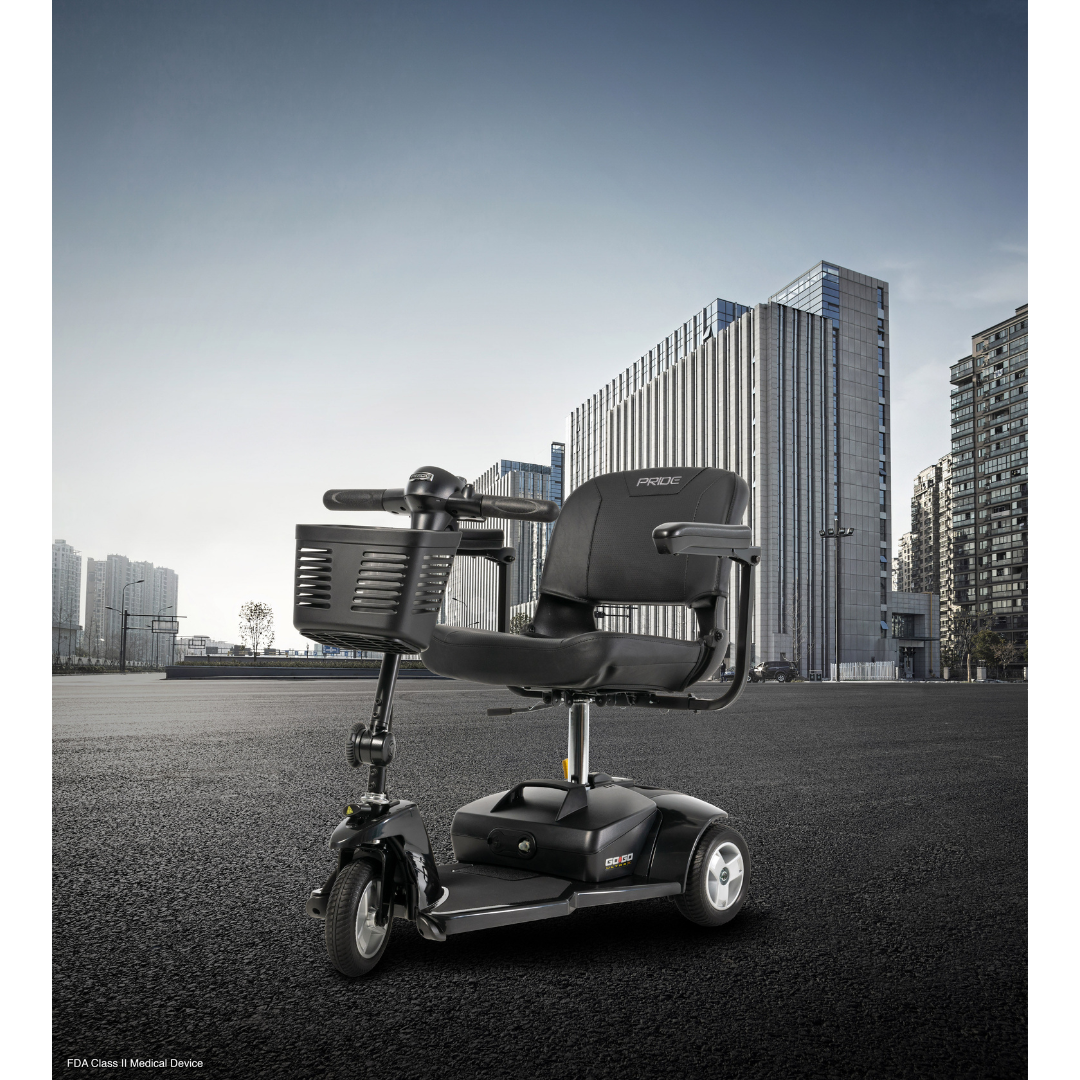 A Pride Mobility Go Go® Ultra X 3-Wheel Scooter is parked on an empty urban street, showcasing economy-class features like a seat, handlebars, and front basket. Tall modern buildings frame its sleek presence against a clear blue sky, epitomizing urban mobility.