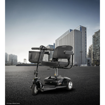 A Pride Mobility Go Go® Ultra X 3-Wheel Scooter is parked on an empty urban street, showcasing economy-class features like a seat, handlebars, and front basket. Tall modern buildings frame its sleek presence against a clear blue sky, epitomizing urban mobility.