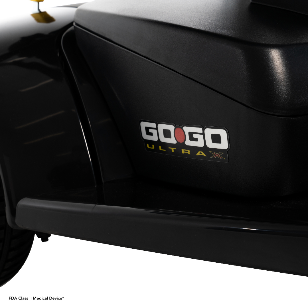 Close-up of the black Pride Mobility Go Go® Ultra X 3-Wheel Scooter with its FDA Class II Medical Device* label at the bottom left. Renowned for its portable design, this economical scooter perfectly combines convenience and affordability.