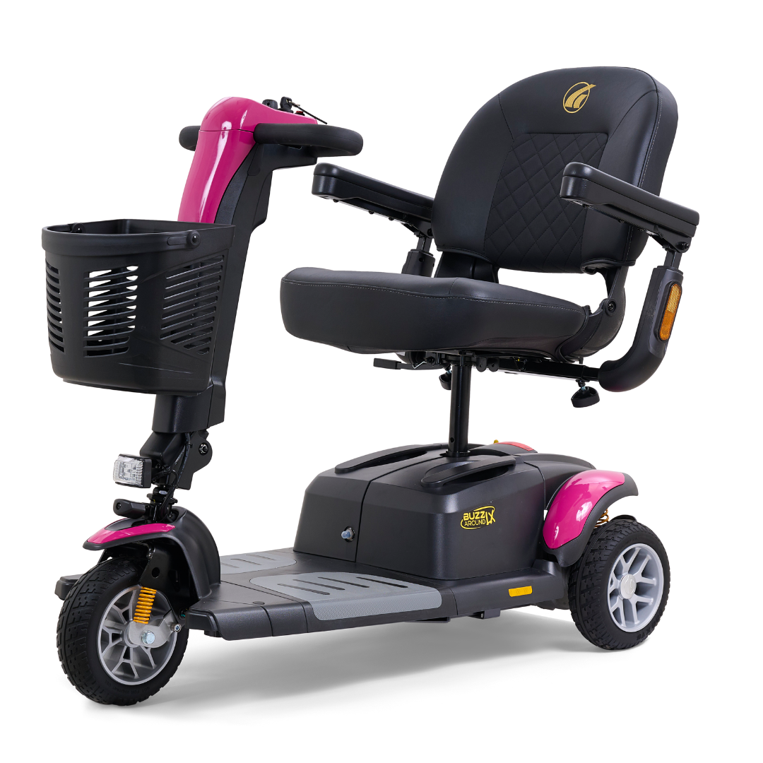 The Golden Buzzaround LX GB119 is a heavy-duty three-wheel portable mobility scooter featuring a luxurious design with a black seat and handlebars. It includes stylish pink accents on the front wheel cover and sides, and is complemented by a front basket, all set against a white background.