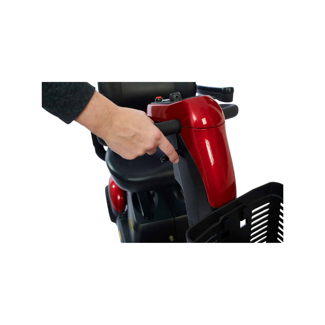 A person maneuvers the Golden Buzzaround LX GB119 - Heavy Duty 3 Wheel Portable Mobility Scooter by holding onto the handlebar. This sophisticated mobility scooter, with its sleek red design, black control panel, and front storage basket, highlights the hand engaged with the controls.