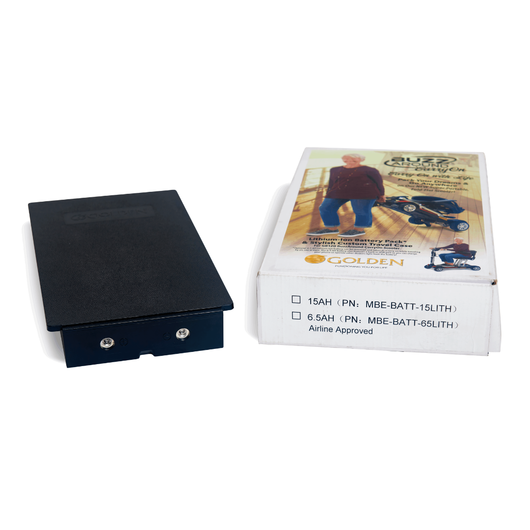 A rectangular black lithium-ion battery rests beside a cardboard box displaying text and an image of a person using the ultra-portable Golden Technologies Portable Buzzaround GB120 Carry-On Travel Scooter indoors. The 15AH model is also highlighted as airline approved.