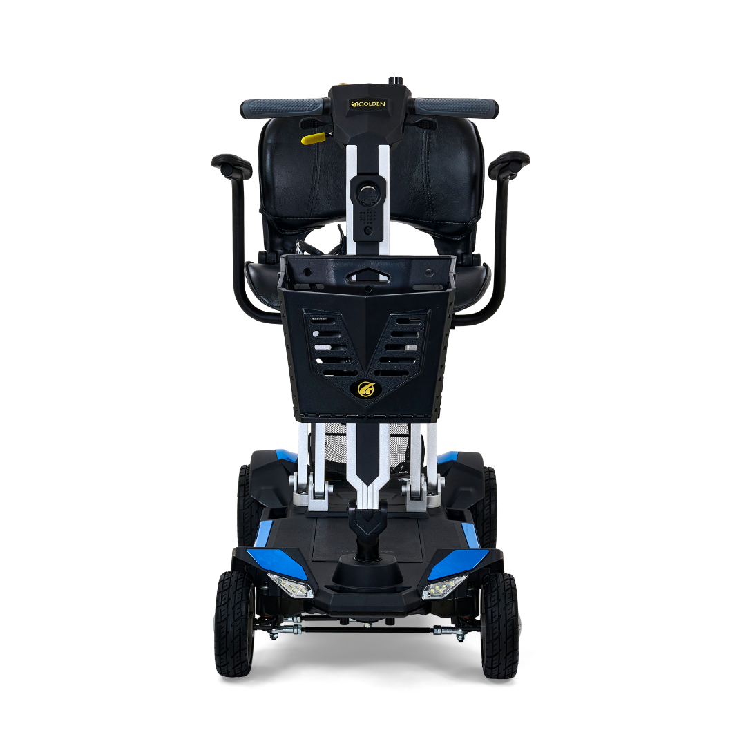 The Golden Technologies Portable Buzzaround GB120 Carry-On Travel Scooter is a ultra-portable mobility solution in black and blue, featuring a sturdy frame with four wheels. It boasts a fold-flat design, padded backrest, ergonomic handlebars, and is powered by a robust lithium-ion battery. The scooter is depicted from the front to highlight its sleek design and durable construction.