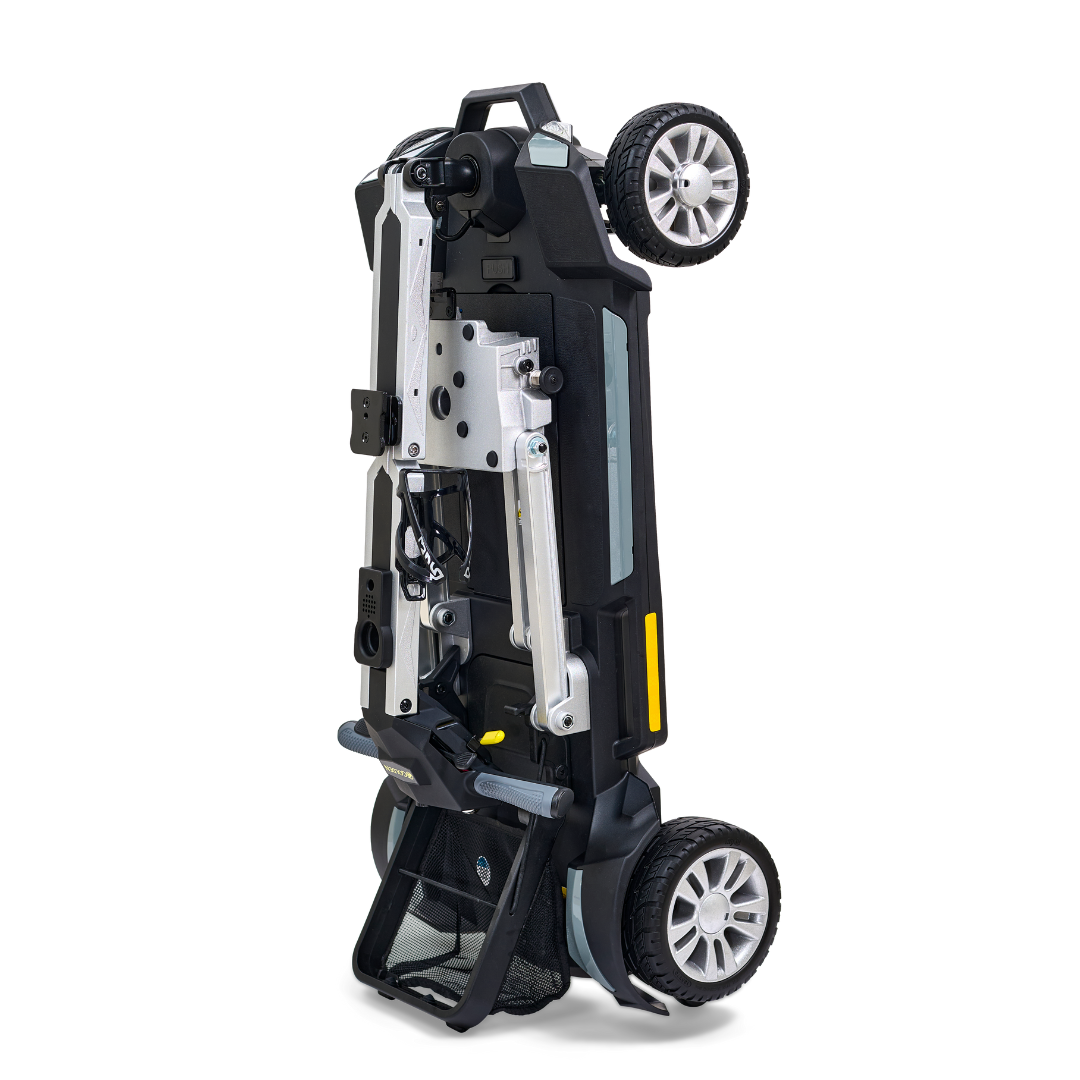 The Golden Technologies Portable Buzzaround GB120 Carry-On Travel Scooter is a compact, ultra-portable device with a sleek black design, supported by a sturdy silver frame. It features two large wheels and two smaller ones for smooth maneuverability. The scooter includes a mesh basket underneath and a convenient handlebar on top, akin to the design of a fold-flat scooter ideal for urban convenience.