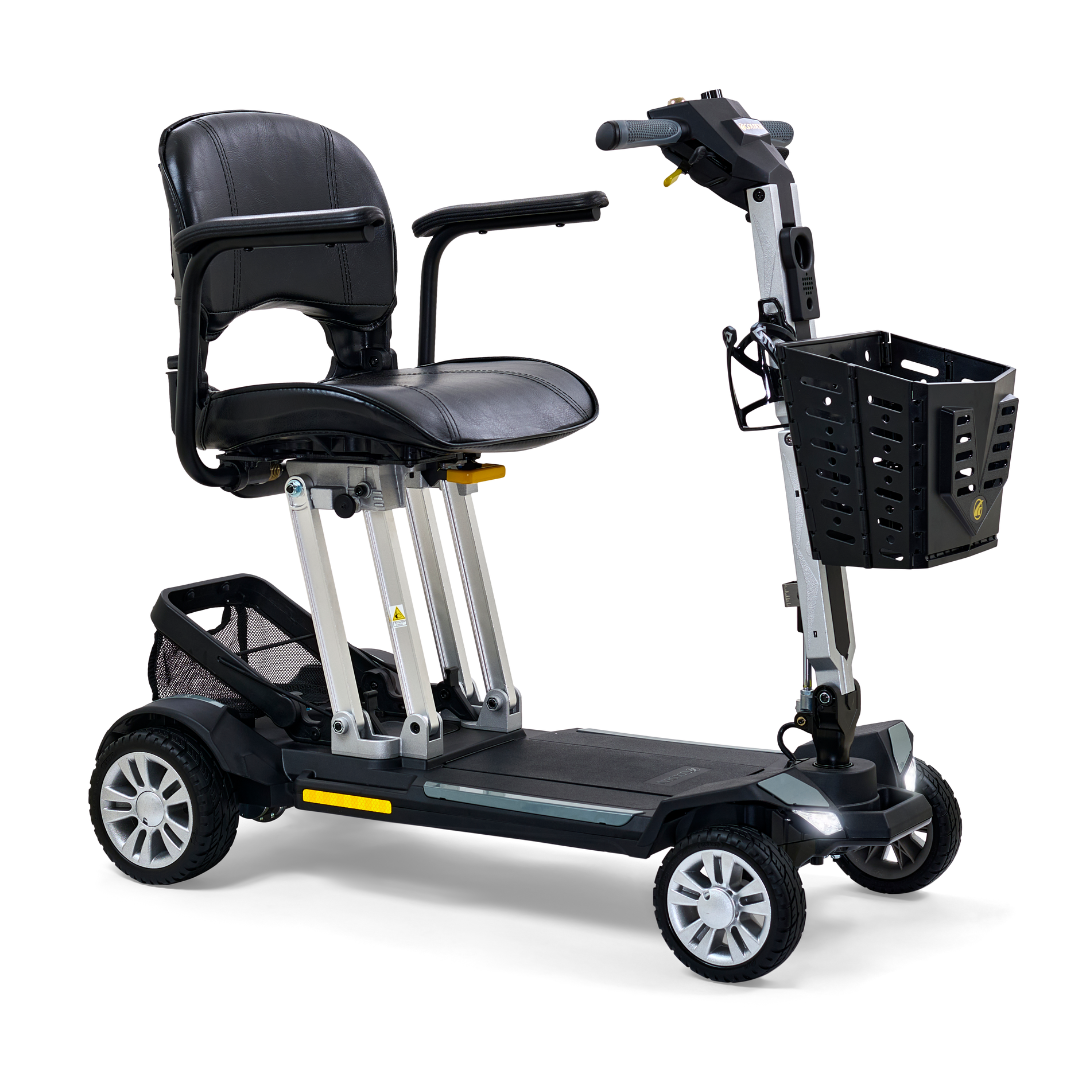The Golden Technologies Portable Buzzaround GB120 Carry-On Travel Scooter is a compact and ultra-portable option featuring a black fold-flat design with four wheels. It includes a padded seat with armrests and a small basket at the front, enhancing both comfort and convenience. This scooter is designed for easy maneuverability and transport, boasting metallic accents, a sturdy frame, and a long-lasting lithium-ion battery.