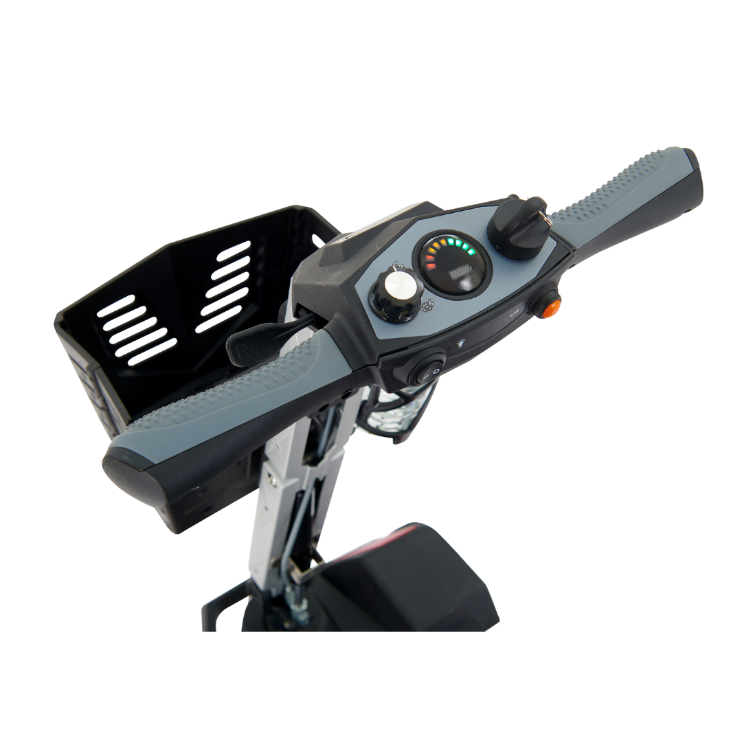 The image showcases the handle and control panel of the Golden Technologies Portable Buzzaround GB120 Carry-On Travel Scooter. The handlebars have gray grips, and the panel features a speedometer and controls. A small basket is attached at the front, complementing its fold-flat design for convenience.