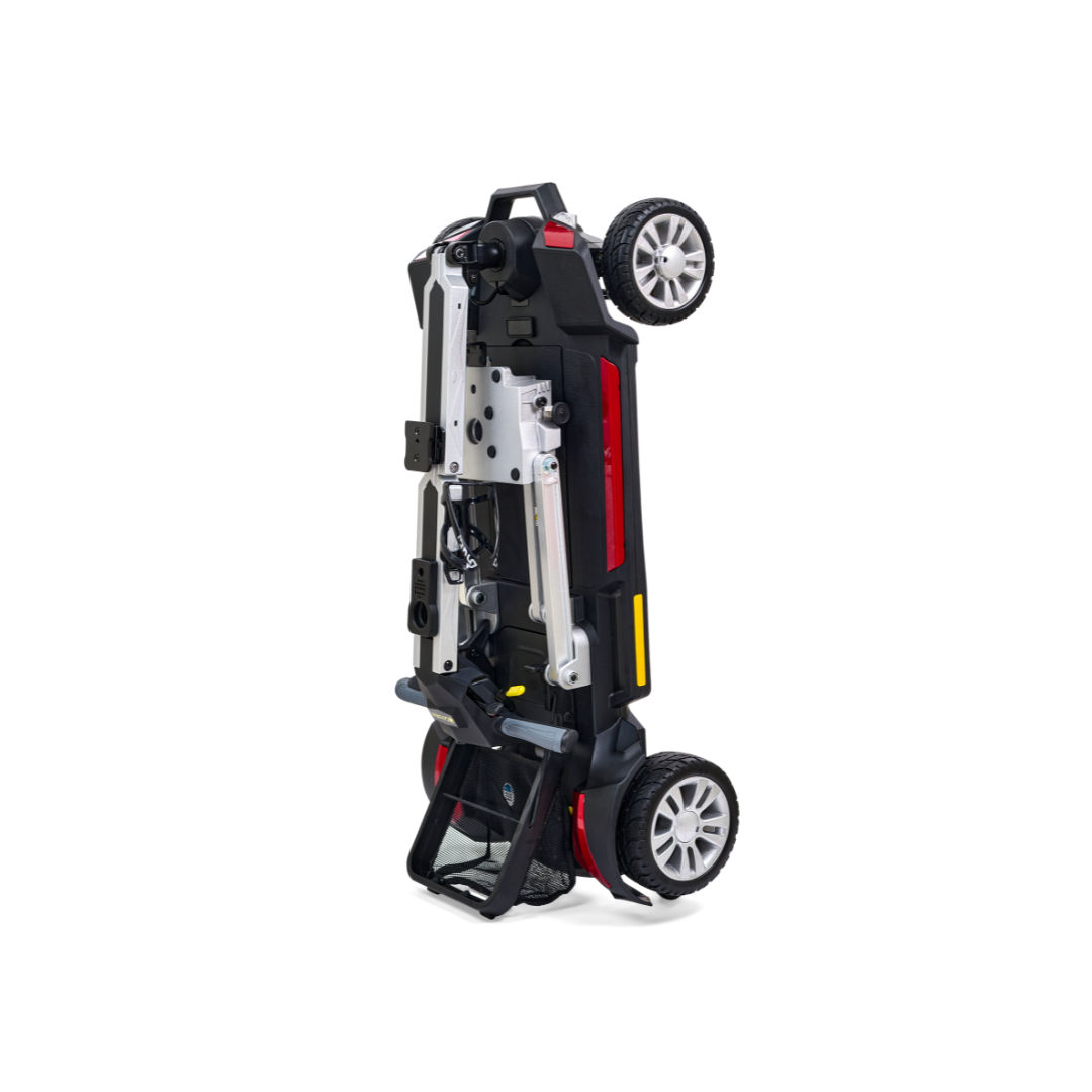 A folded black and red Golden Technologies Portable Buzzaround GB120 Carry-On Travel Scooter stands upright, its two wheels visible. The aluminum frame and handle are prominent, with a compact seat that enhances its ultra-portable design. Ideal for easy storage, it offers the convenience of a fold-flat scooter without compromising on style or function.