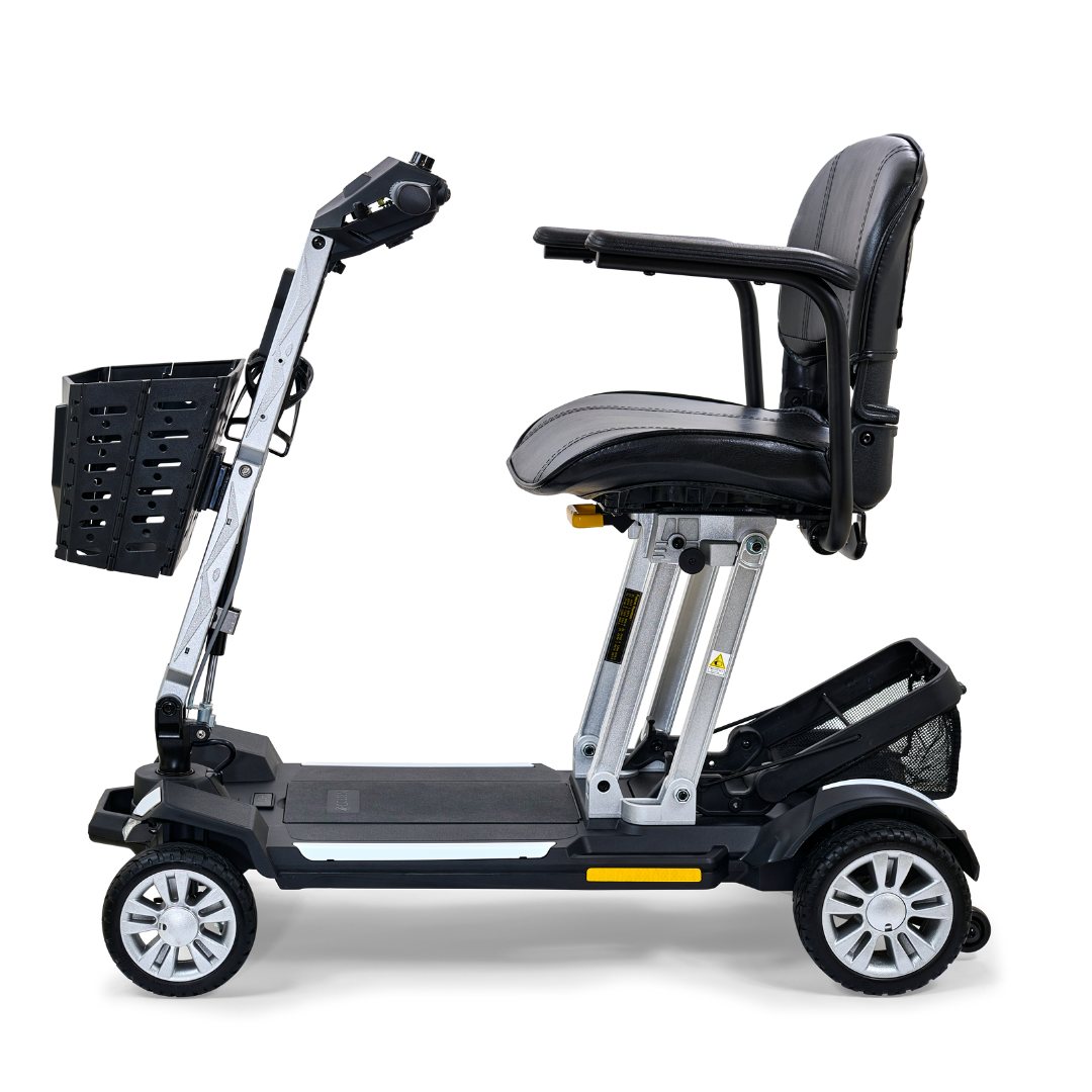 The Golden Technologies Portable Buzzaround GB120 Carry-On Travel Scooter is a compact, foldable mobility scooter equipped with a black seat, four wheels, and a front basket. It includes an ultra-portable lithium-ion battery and is pictured in profile view against a white background.