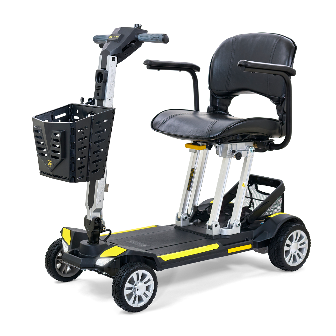 Introducing the Golden Technologies Portable Buzzaround GB120 Carry-On Travel Scooter: This ultra-portable mobility scooter features a black padded seat, armrests, and a convenient small front basket. It showcases a silver frame with striking yellow accents and is equipped with four wheels for stability. Powered by a lithium-ion battery, it includes handlebars fitted with an intuitive control panel for easy maneuverability.