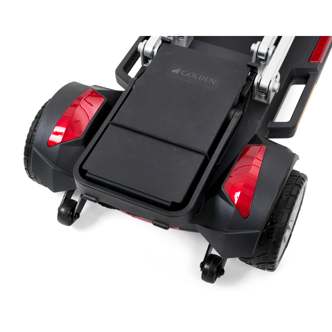 Close-up of the rear end of a Golden Technologies Portable Buzzaround GB120 Carry-On Travel Scooter, highlighting its black and red color scheme, two wheels, red reflectors, and a central platform displaying the word Golden. This ultra-portable model features a sleek design with a lithium-ion battery for efficient travel.