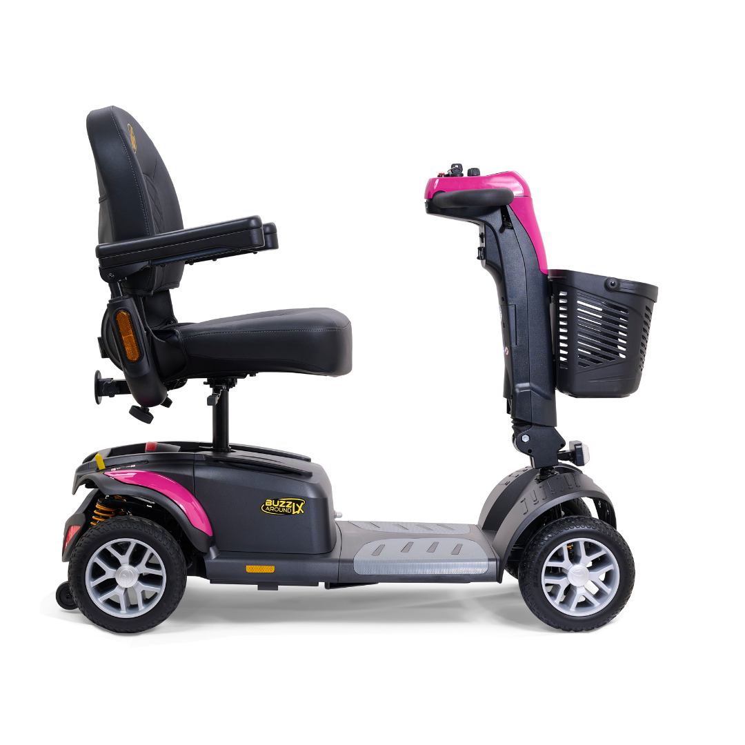 Side view of the Golden Buzzaround LX GB149 - Heavy Duty 4 Wheel Portable Mobility Scooter showcasing a black seat, backrest, and armrests. The scooter features a pink accent on the handlebars and comes with a front-mounted black basket. This portable travel mobility scooter has four wheels, a grey base, and includes an adjustable tiller for enhanced convenience.