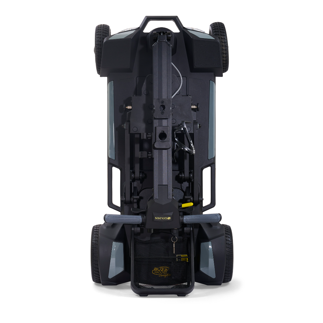 A top-down view of the Golden Buzzaround GB220 CarryOn HD Travel Scooter, folded and standing upright on its rear wheels, displaying the underside, wheelbase, and an attached storage bag at the bottom.