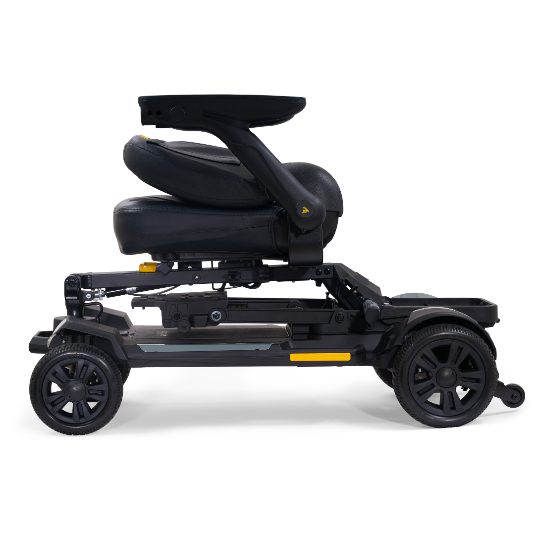 The Golden Buzzaround GB220 CarryOn HD Travel Scooter is shown in black, folded from the side with its seat collapsed over the frame and armrests above the wheels for convenient storage or transport.