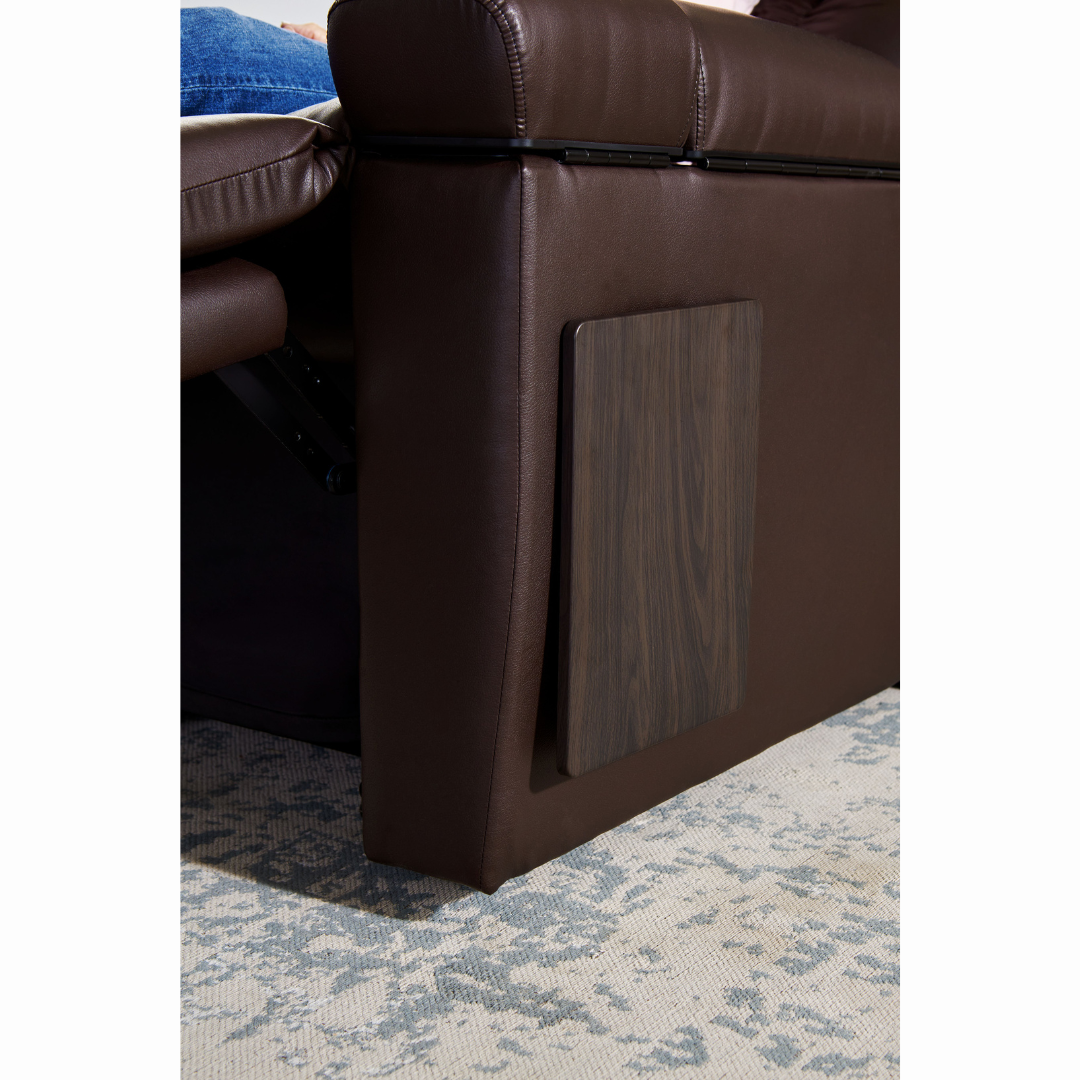 Side view of a dark brown Golden Cloud+ PR511 Recliner with Lift Assist - Medium Wide on a light patterned rug. It features an extended footrest with a persons leg in jeans resting on it, easily adjustable using the intuitive AutoDrive hand control for tailored comfort.