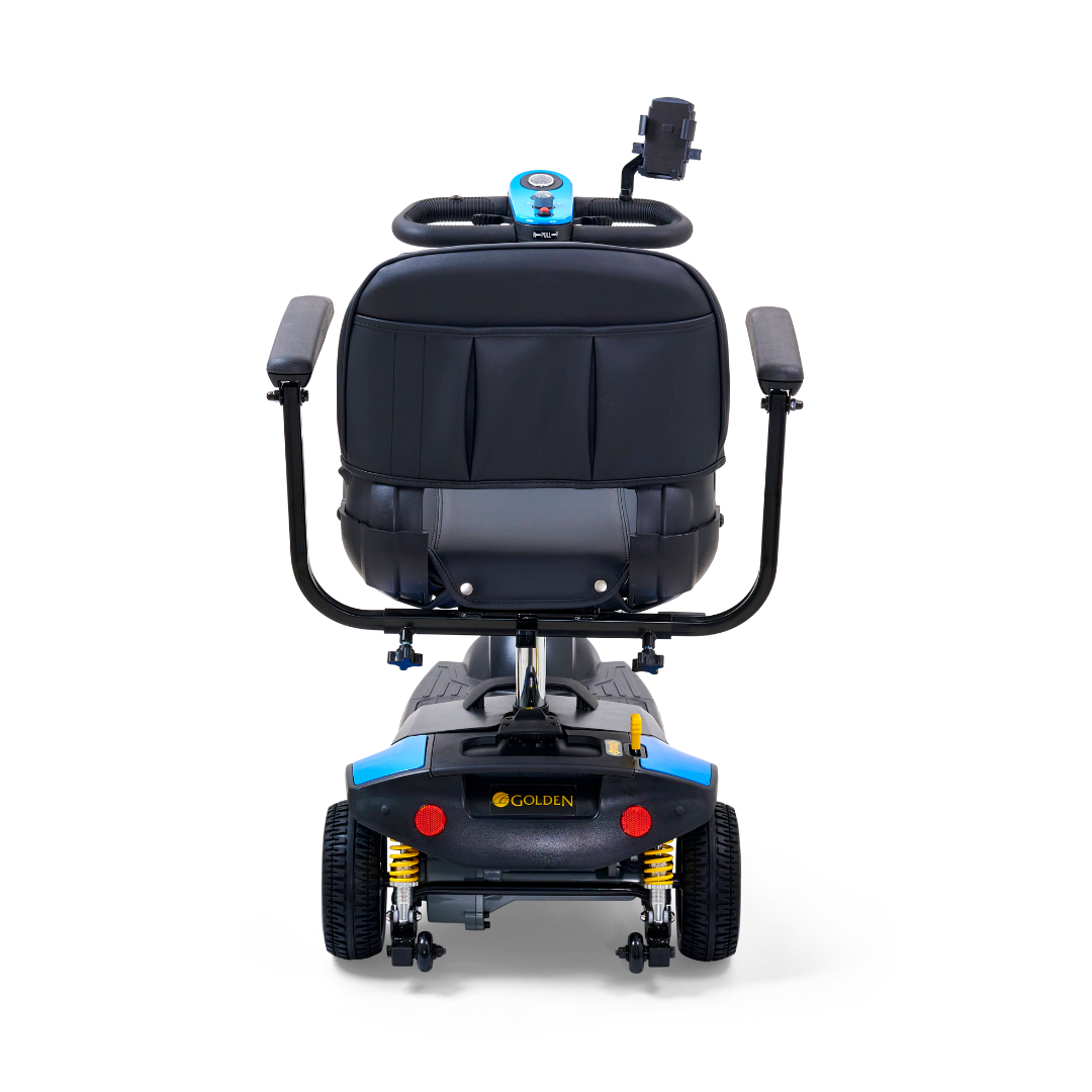 The rear view of the Golden Tech GB121 Buzzaround XLS HD shows a mobility scooter with a blue backrest, dual armrests, and Comfort Spring Suspension on its four wheels. It features an extended range battery, a control panel on the handlebars, and the reputable Golden brand name emphasizing durability.