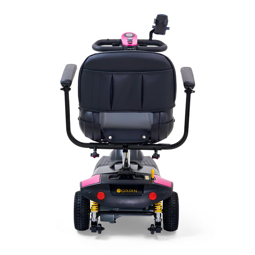 The Golden Tech GB121 Buzzaround XLS HD 3-Wheel Portable Scooter features a black rear view with pink accents, a cushioned seat, dual armrests, visible back wheels, and a Delta tiller on the control panel. It boasts Comfort Spring Suspension for smooth riding.