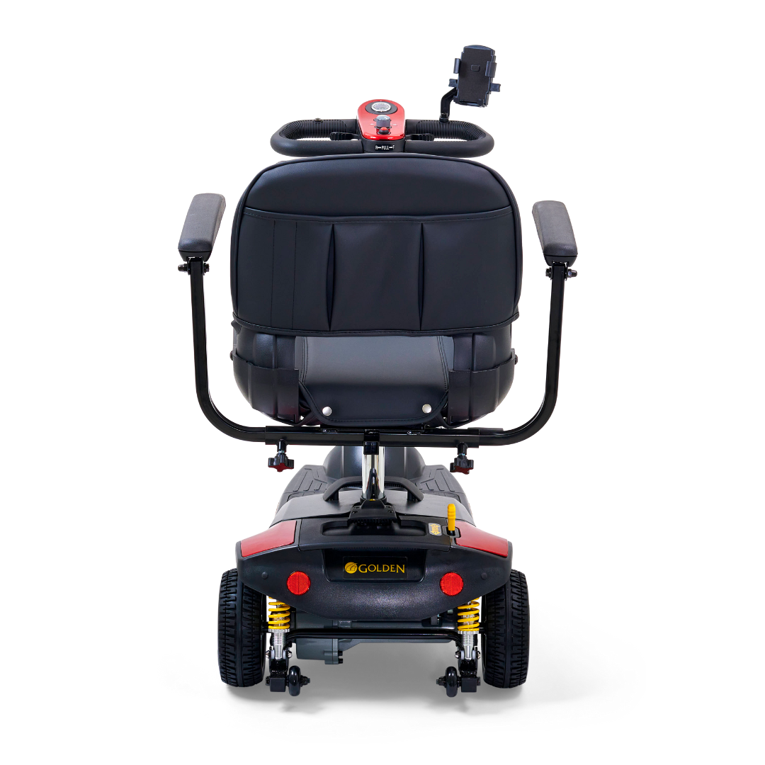 A rear view of the Golden Tech GB121 Buzzaround XLS HD 3-wheel portable scooter showcases a sleek black design with gold accents, Delta tiller, and storage pocket on the seat back. The handlebars and rear wheels enhance its appearance, with Golden proudly printed on the base.