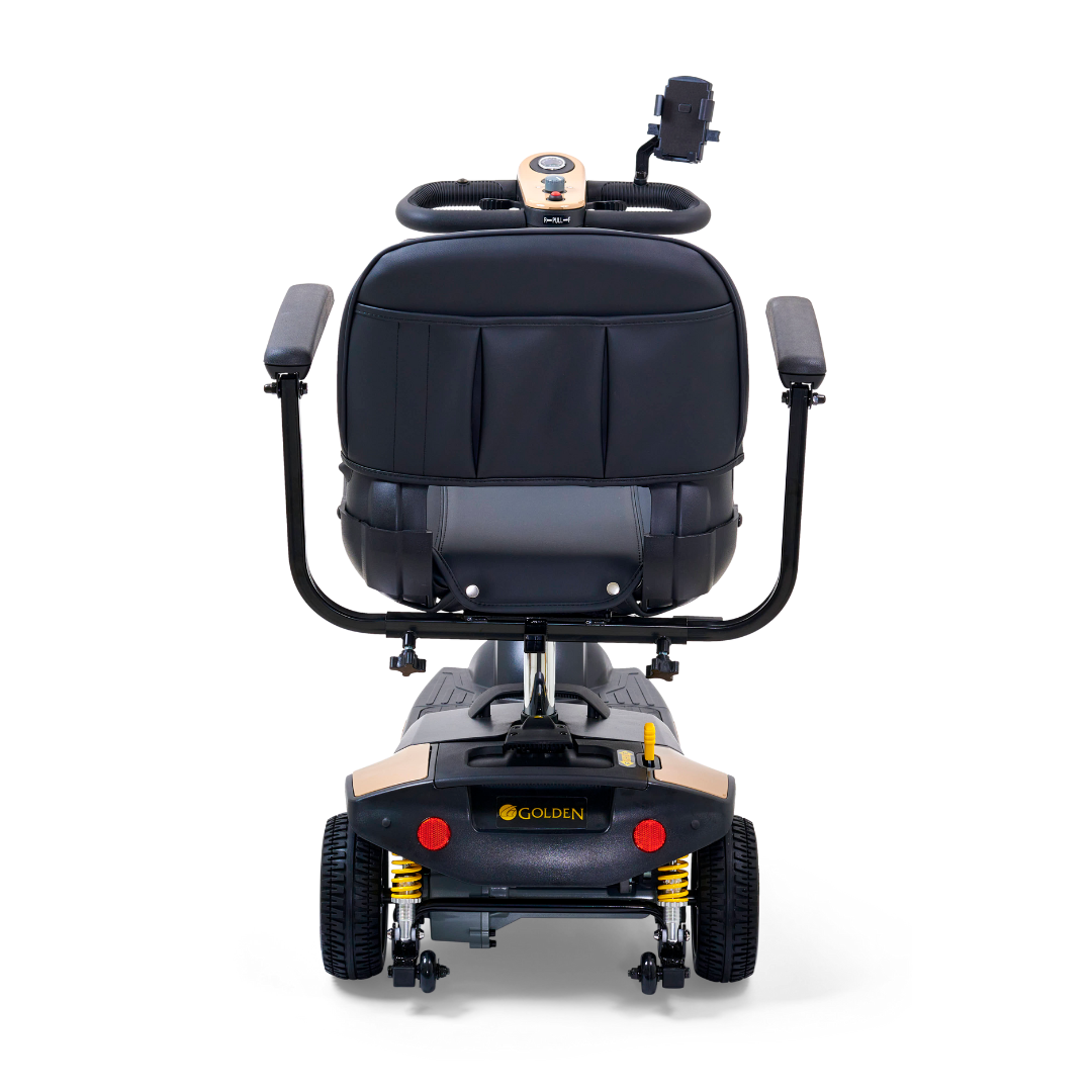 The rear view of the Golden Tech GB121 Buzzaround XLS HD 3-Wheel Portable Scooter features a stadium-style seat with armrests, control panel, backrest, and Comfort Spring Suspension. It also displays the Golden logo and has a small rear light for safety.