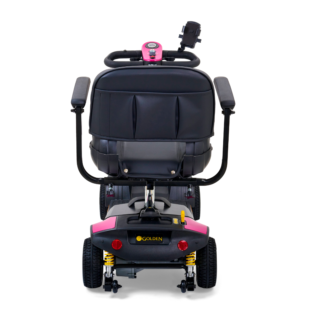 The rear view of the Golden Tech GB124 Buzzaround XLS HD 4-Wheel Scooter, in black with pink trim, features armrests, a backrest, rear-view mirrors, and visible wheels with Comfort Spring Suspension. Its branding highlights the thoughtful design.