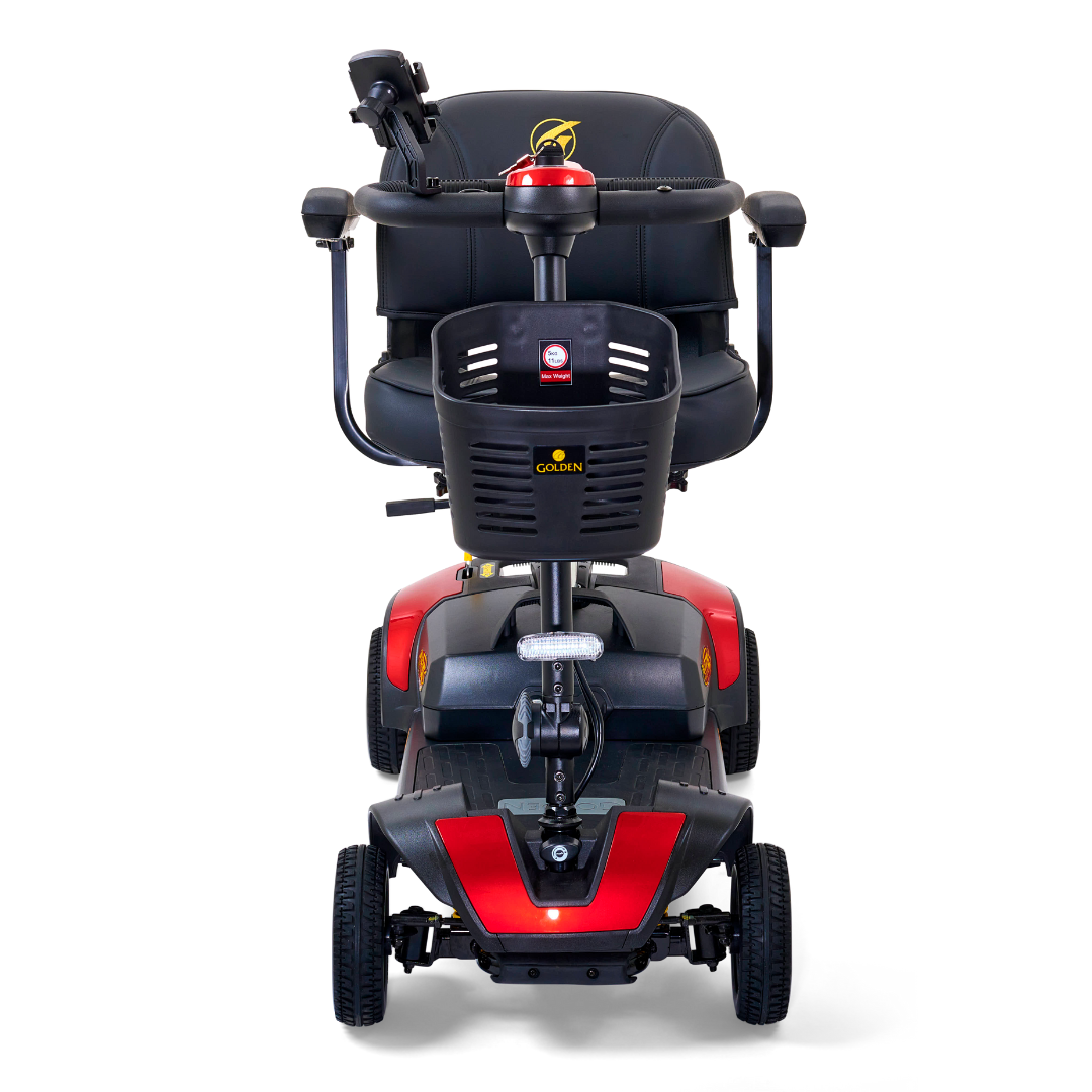 Front view of the Golden Tech GB124 Buzzaround XLS HD 4-Wheel Portable Scooter in red-and-black with a padded black seat, armrests, and buttons on a delta tiller handle. It features Comfort Spring Suspension, and is set against a white background.