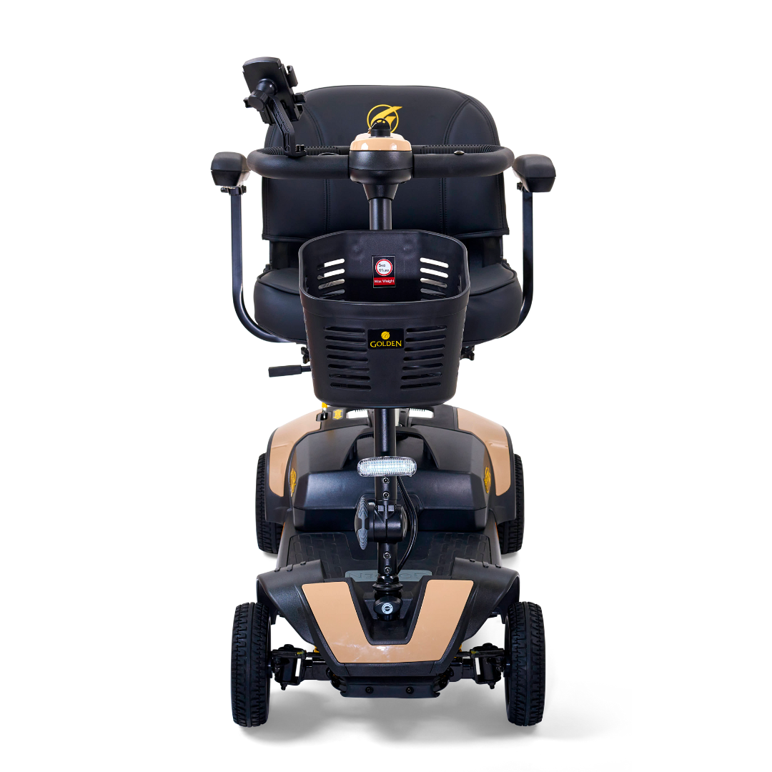 The Golden Tech GB124 Buzzaround XLS HD showcases a compact, black-and-beige design with a comfortable seat, delta tiller handlebars featuring controls, and four stable wheels. Enhanced by Comfort Spring Suspension, the iconic Golden logo is prominently displayed on the front panel.